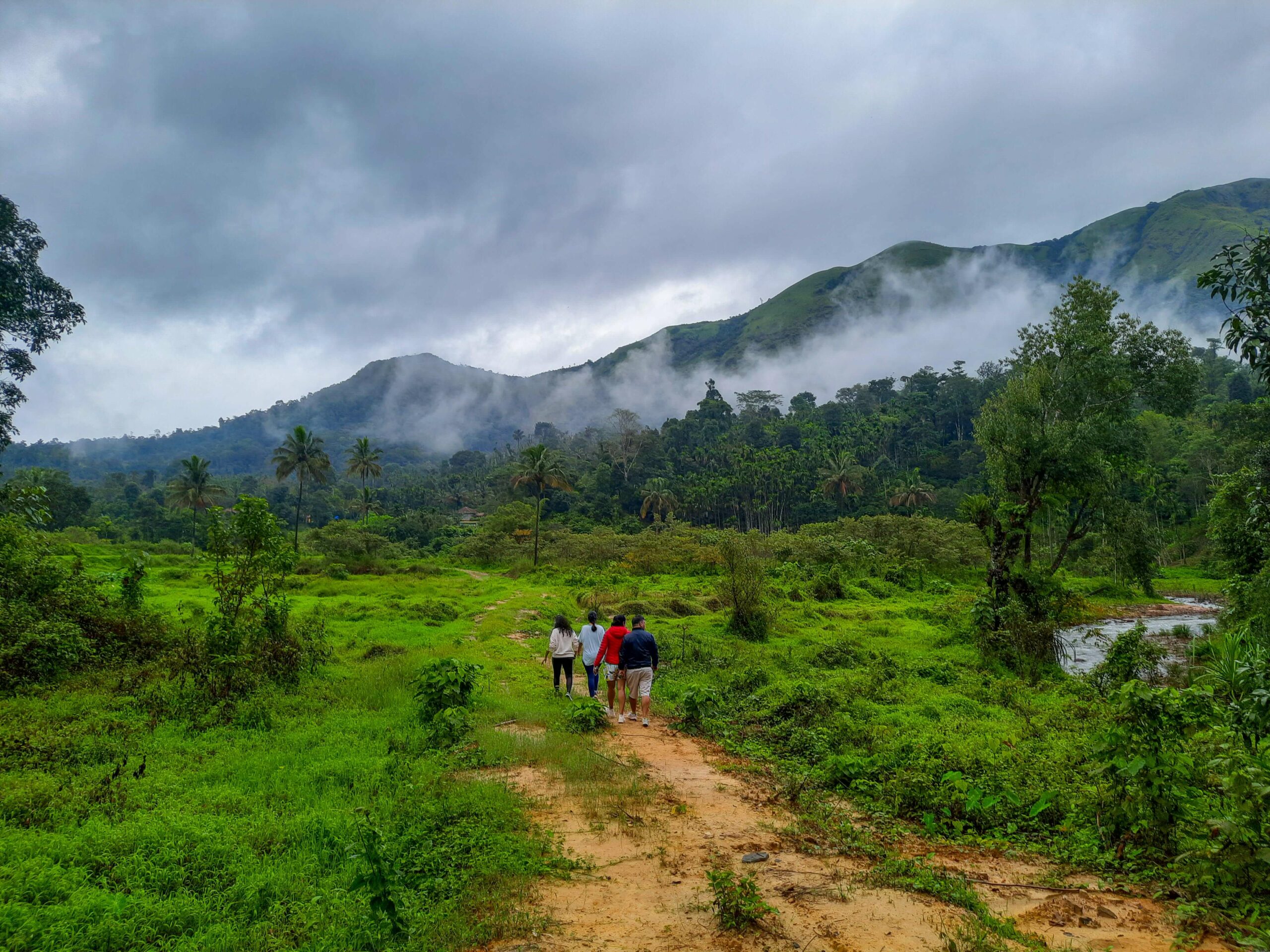 Group walking dirt path in green valley. RiverMist Resorts.