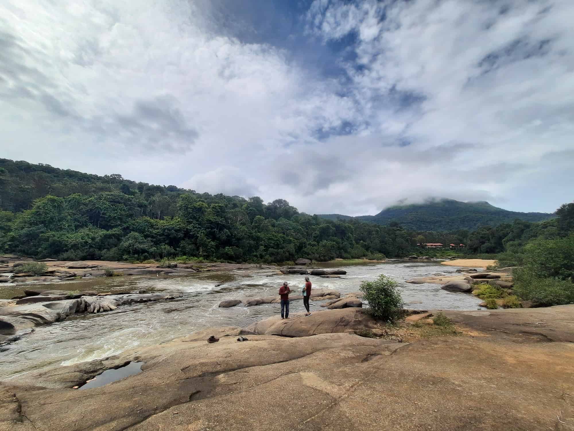 Guests on Ambaa Teertha river rocks. RiverMist Resorts guide.
