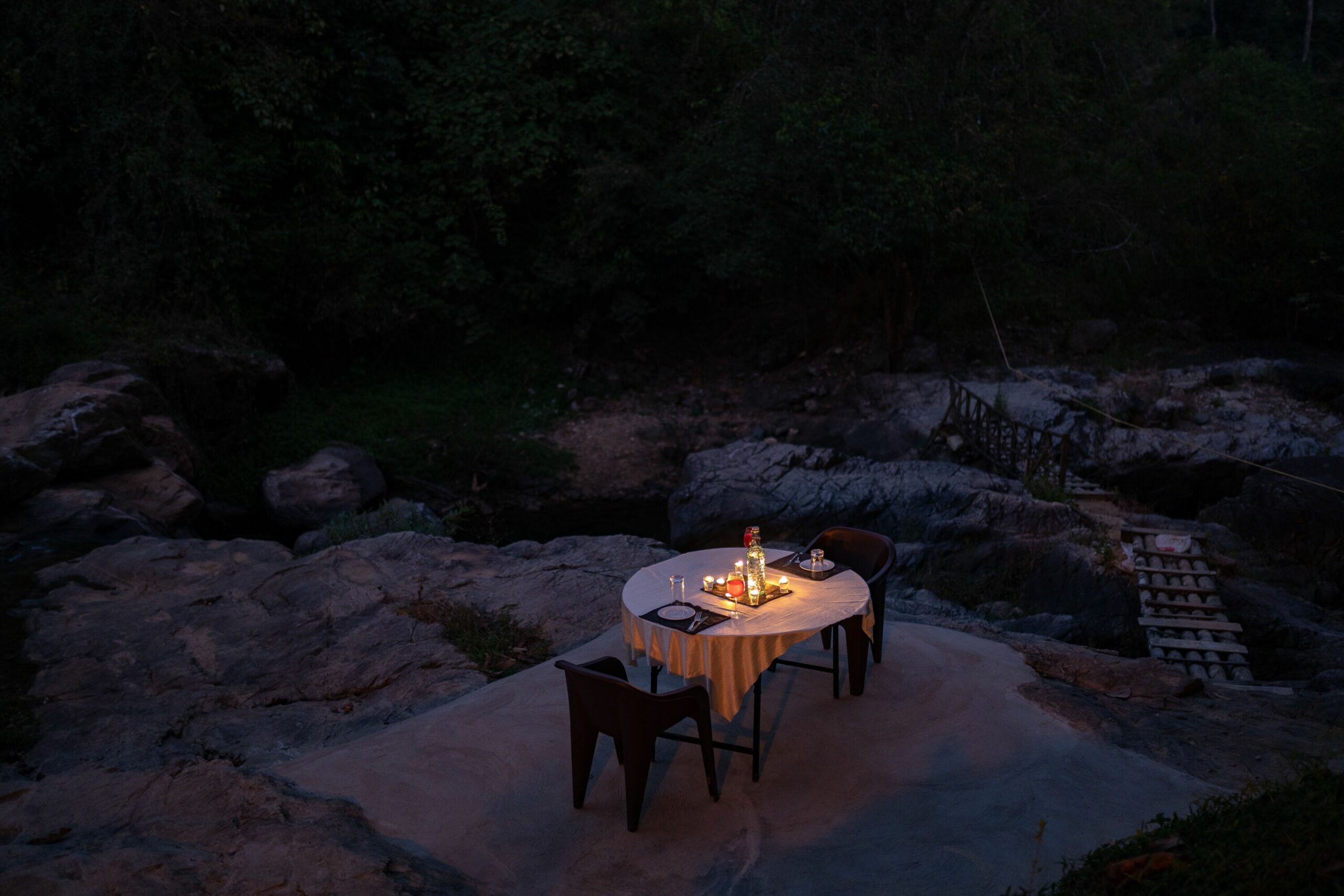 Intimate candlelit dinner on river rocks. RiverMist Resorts.
