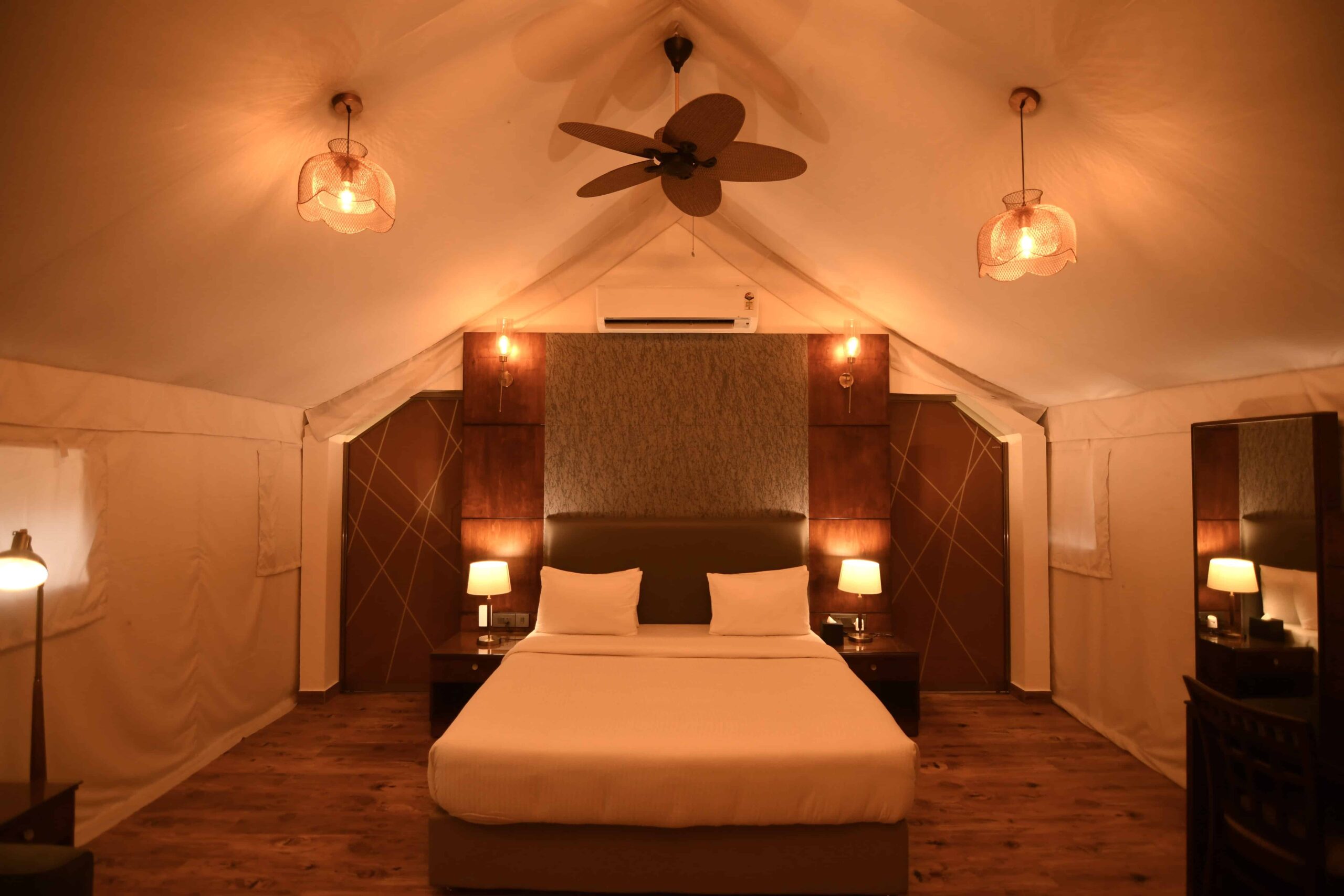 Warmly lit luxury tent room interior. RiverMist Resorts glamping.