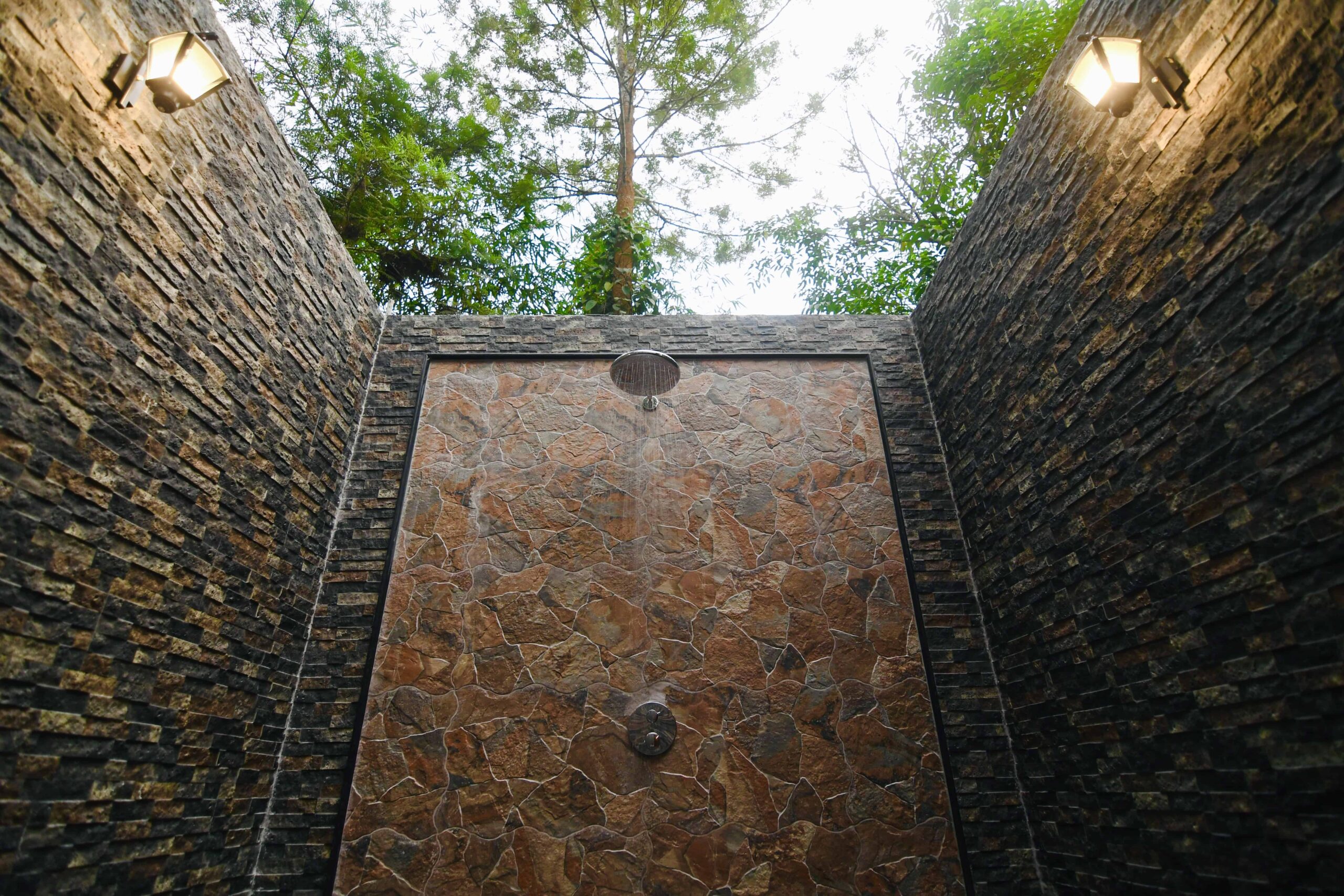 Luxury outdoor shower with stone walls. RiverMist Resorts.