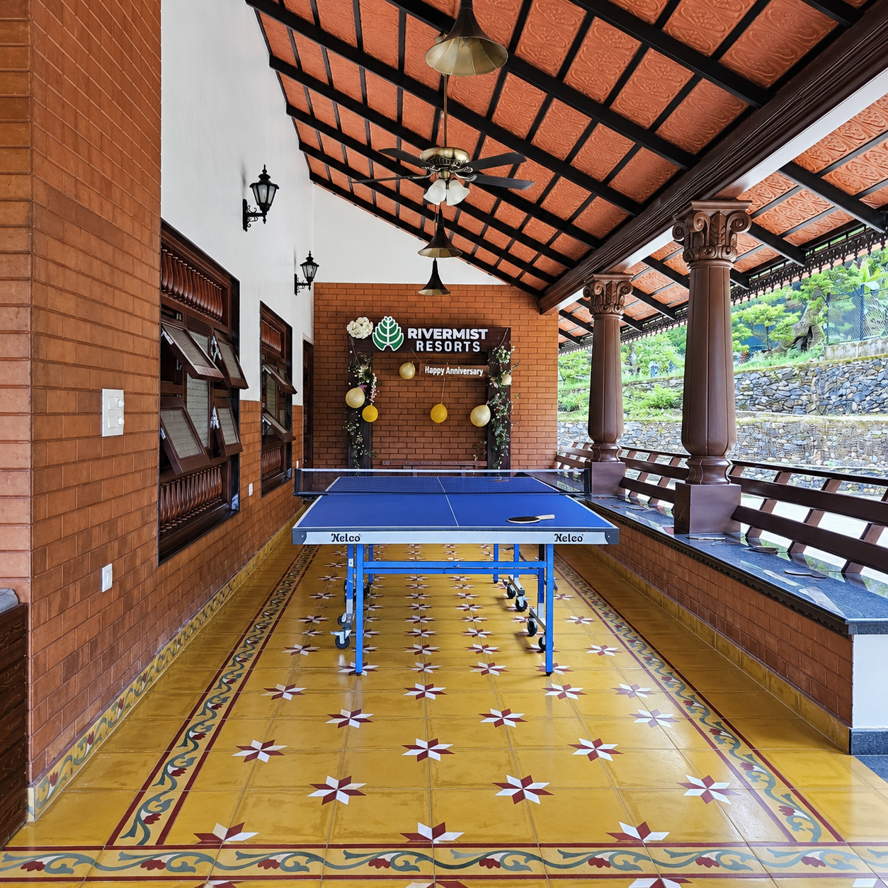 Table tennis area on a covered veranda with patterned tiled flooring at RiverMist Resorts